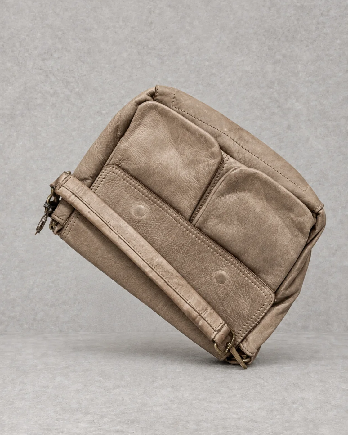 Bolso taupe de piel sobre fondo cemento gris, vista exterior