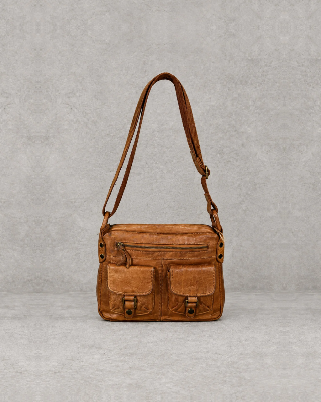 Bolso marrón de piel sobre fondo cemento gris, vista frontal