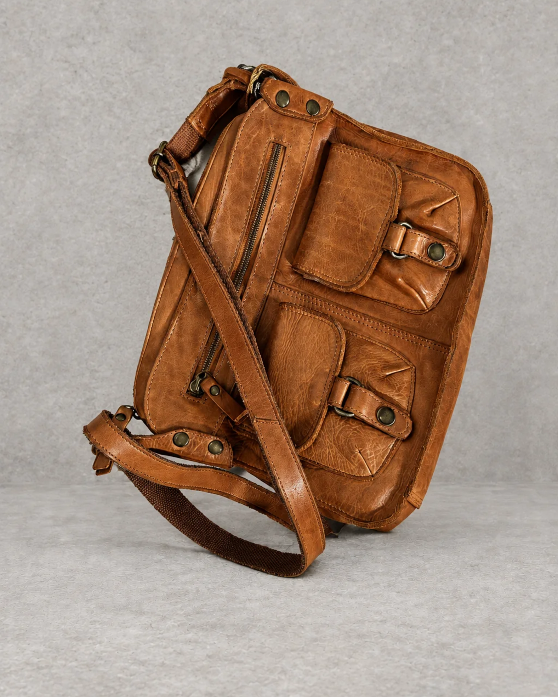Bolso marrón de piel sobre fondo cemento gris, vista exterior