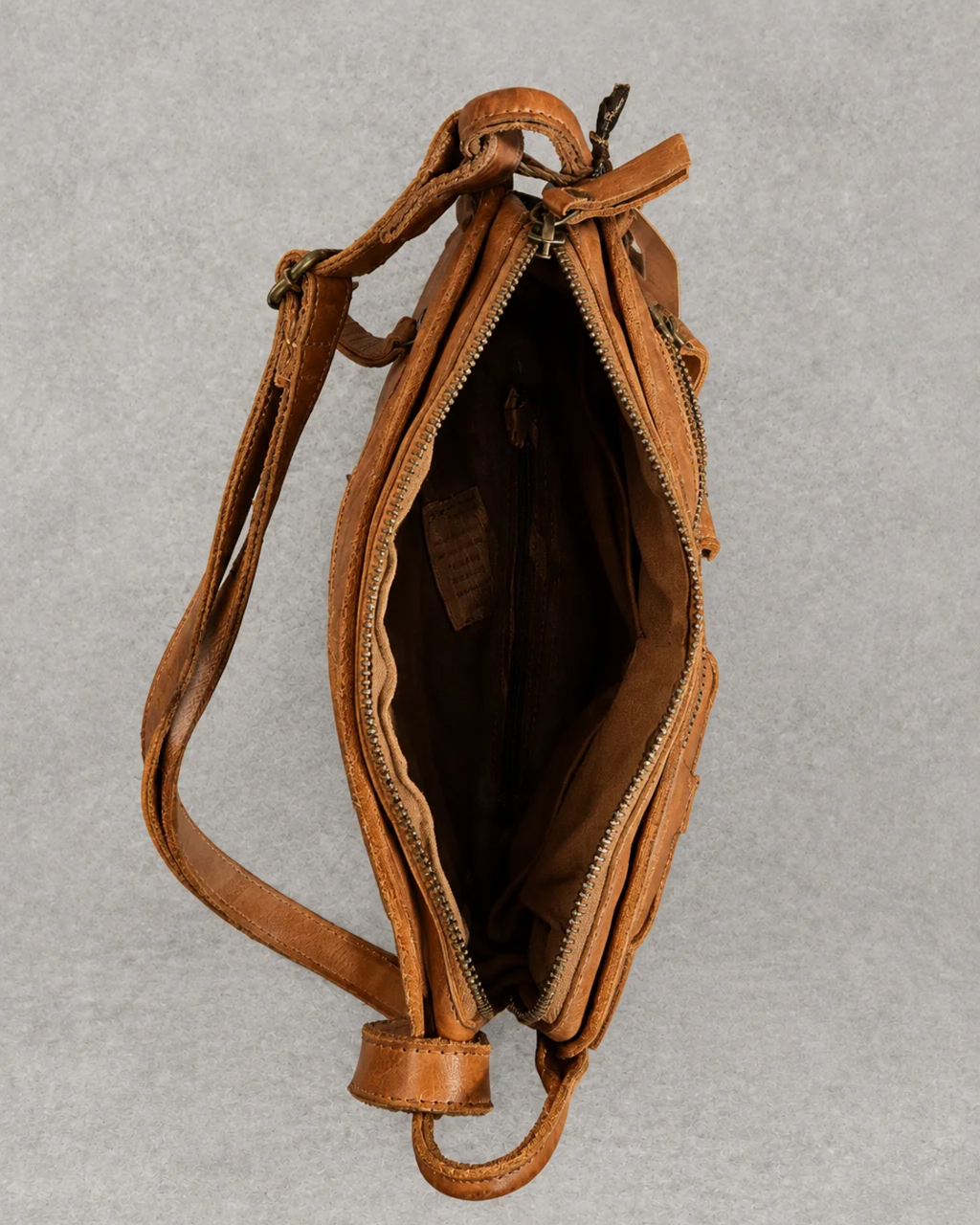 Bolso marrón de piel abierto sobre fondo cemento gris, vista interior